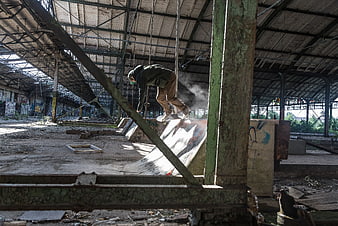 Skateboarder Grinding Ramp in Abandoned Industrial Warehouse