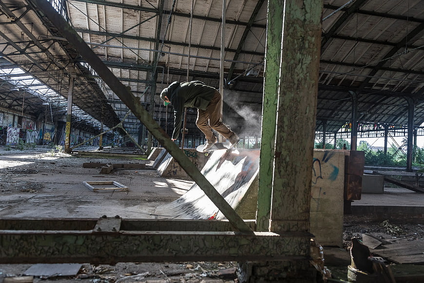 Skateboarder Grinding Ramp in Abandoned Industrial Warehouse