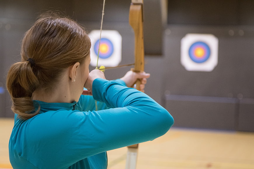 Woman practicing archery with wooden bow and arrow