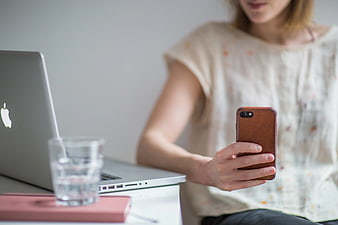 Woman Using Smartphone at Desk with Laptop