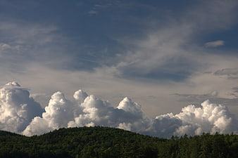 Dramatic Cumulus Clouds Over Green Forested Hills