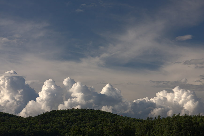 Dramatic Cumulus Clouds Over Green Forested Hills