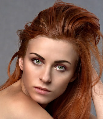 Close-up portrait of a woman with red hair and green eyes