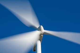 Close-up of a spinning white wind turbine against a clear blue sky