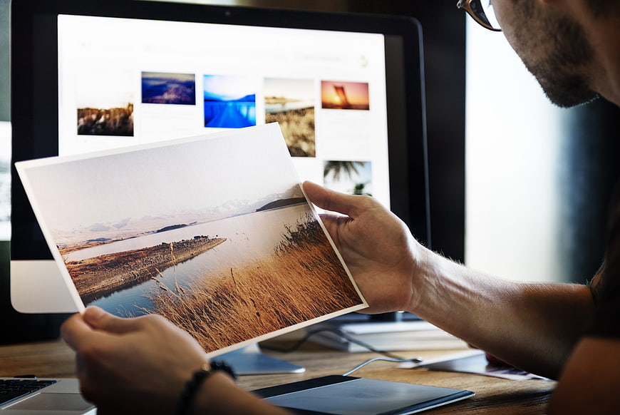 Graphic Designer Comparing Printed Photo with Digital Screen