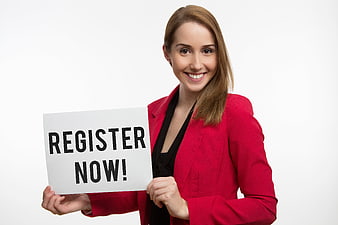 Smiling businesswoman in red blazer holding register now sign