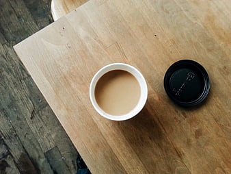 Top view of coffee cup with lid on wooden table