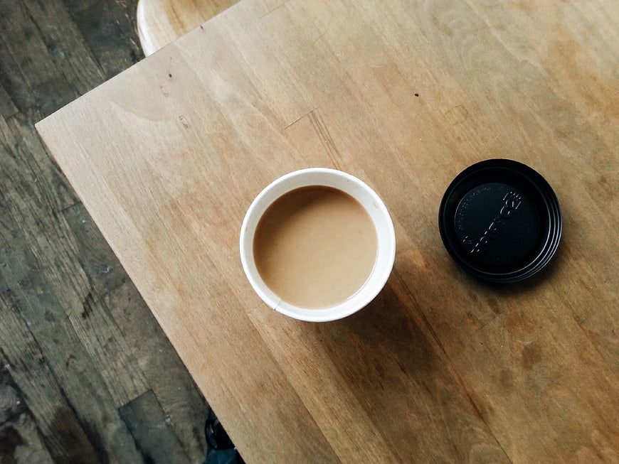 Top view of coffee cup with lid on wooden table