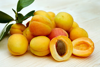 Fresh Ripe Apricots on Wooden Table with Leaves