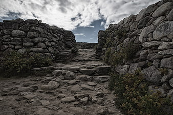 Ancient stone ruins pathway under dramatic cloudy sky