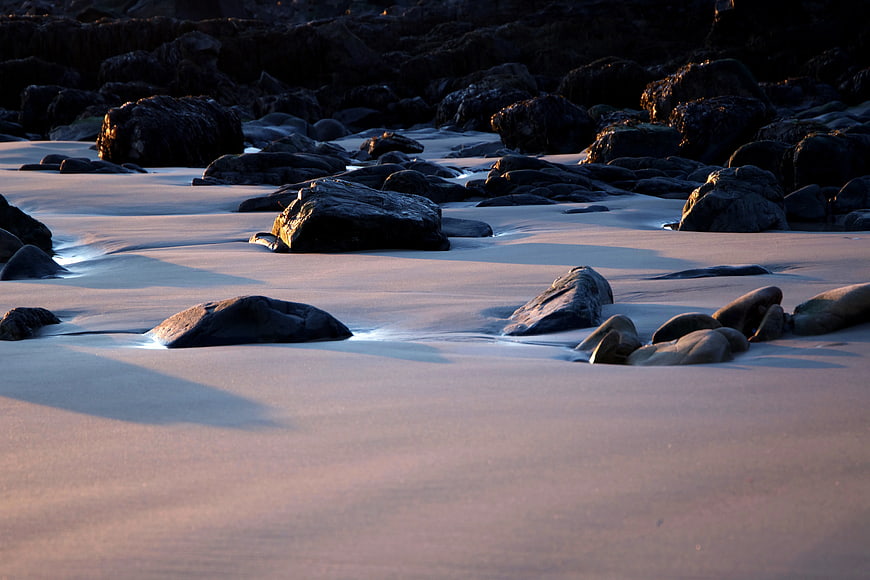 Long Exposure Smooth Water Flowing Over Rocks on Sandy Beach