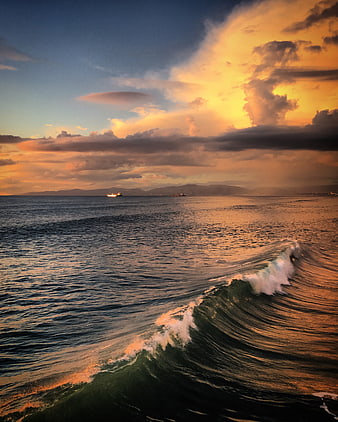Dramatic Ocean Sunset with Rolling Wave and Distant Ships
