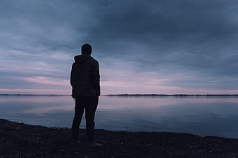 Silhouette of Man Standing by Lake at Dusk