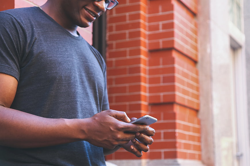 Man Using Smartphone Against Brick Wall