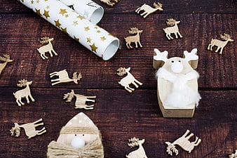 Christmas wrapping paper and wooden reindeer ornaments on wood