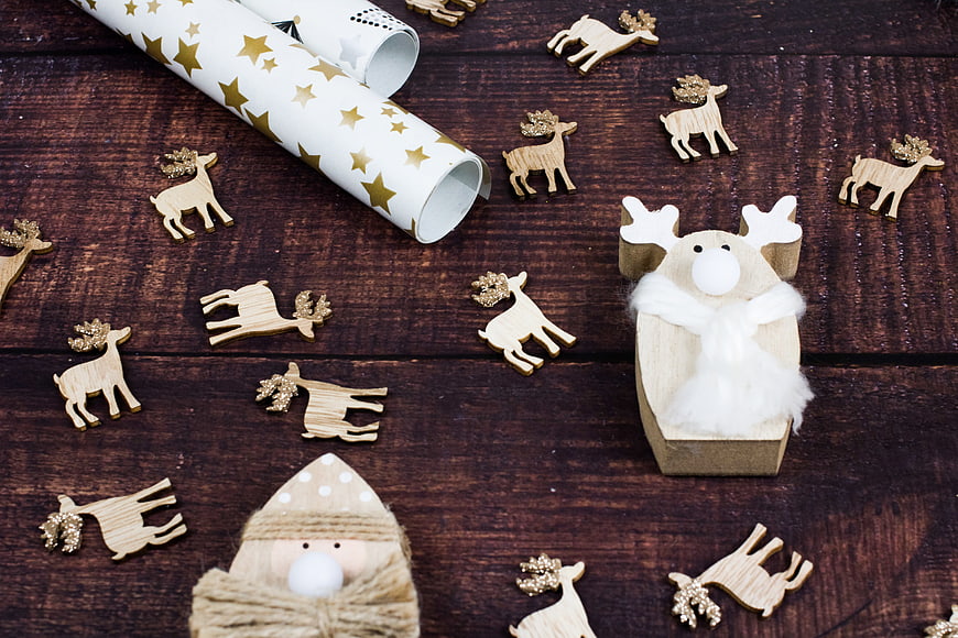 Christmas wrapping paper and wooden reindeer ornaments on wood