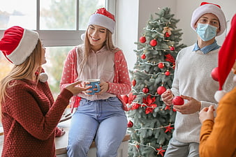 Friends celebrating Christmas with masks and Santa hats