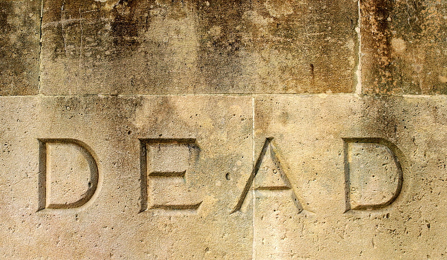 Carved word DEAD on weathered stone wall