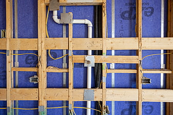 Exposed Wall Framing with Blue Insulation and Plumbing Pipes