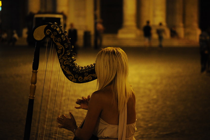 Blonde Woman Playing Harp at Night in City Square