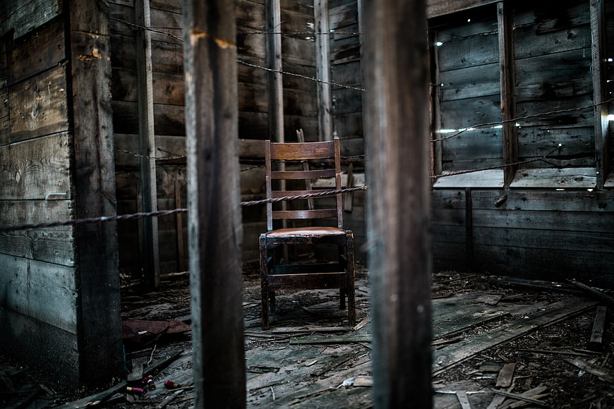 Lonely wooden chair in abandoned rustic cabin interior