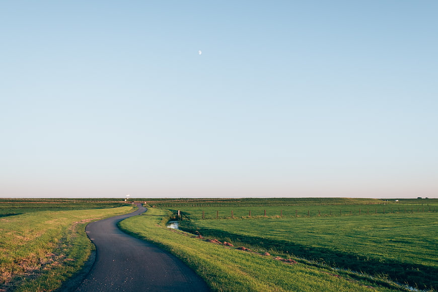 Winding Country Road Through Green Pastures Under Blue Sky