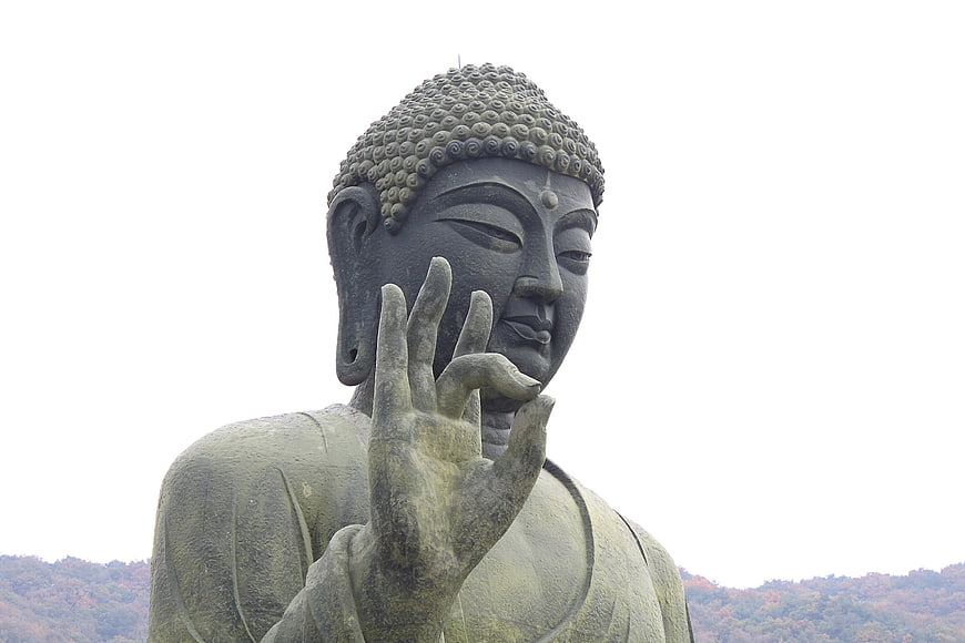 Close-up of Large Buddha Statue with Hand Gesture Against White Sky