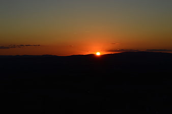 Sunset over dark mountain silhouette with orange sky