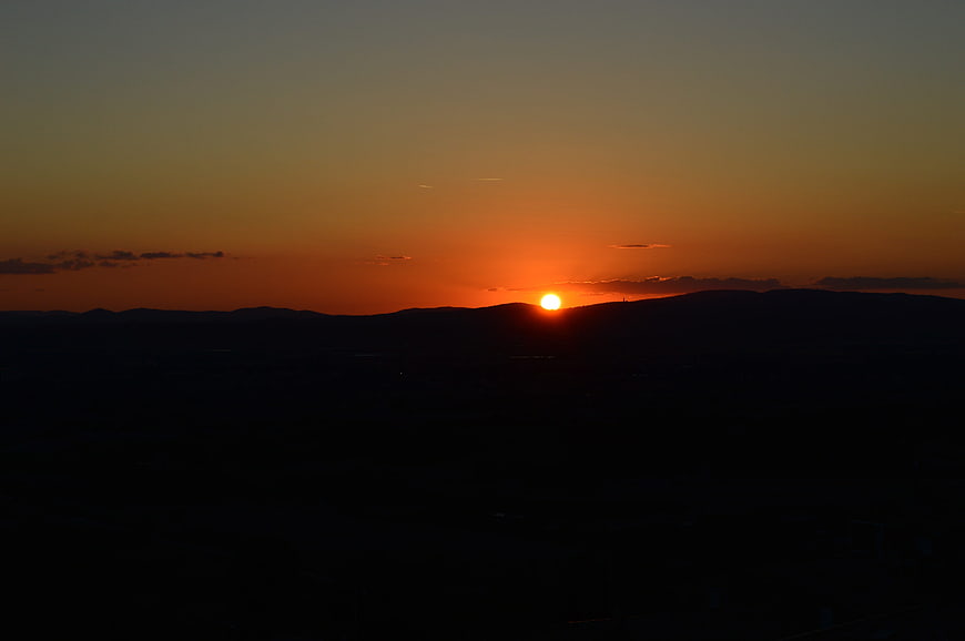 Sunset over dark mountain silhouette with orange sky