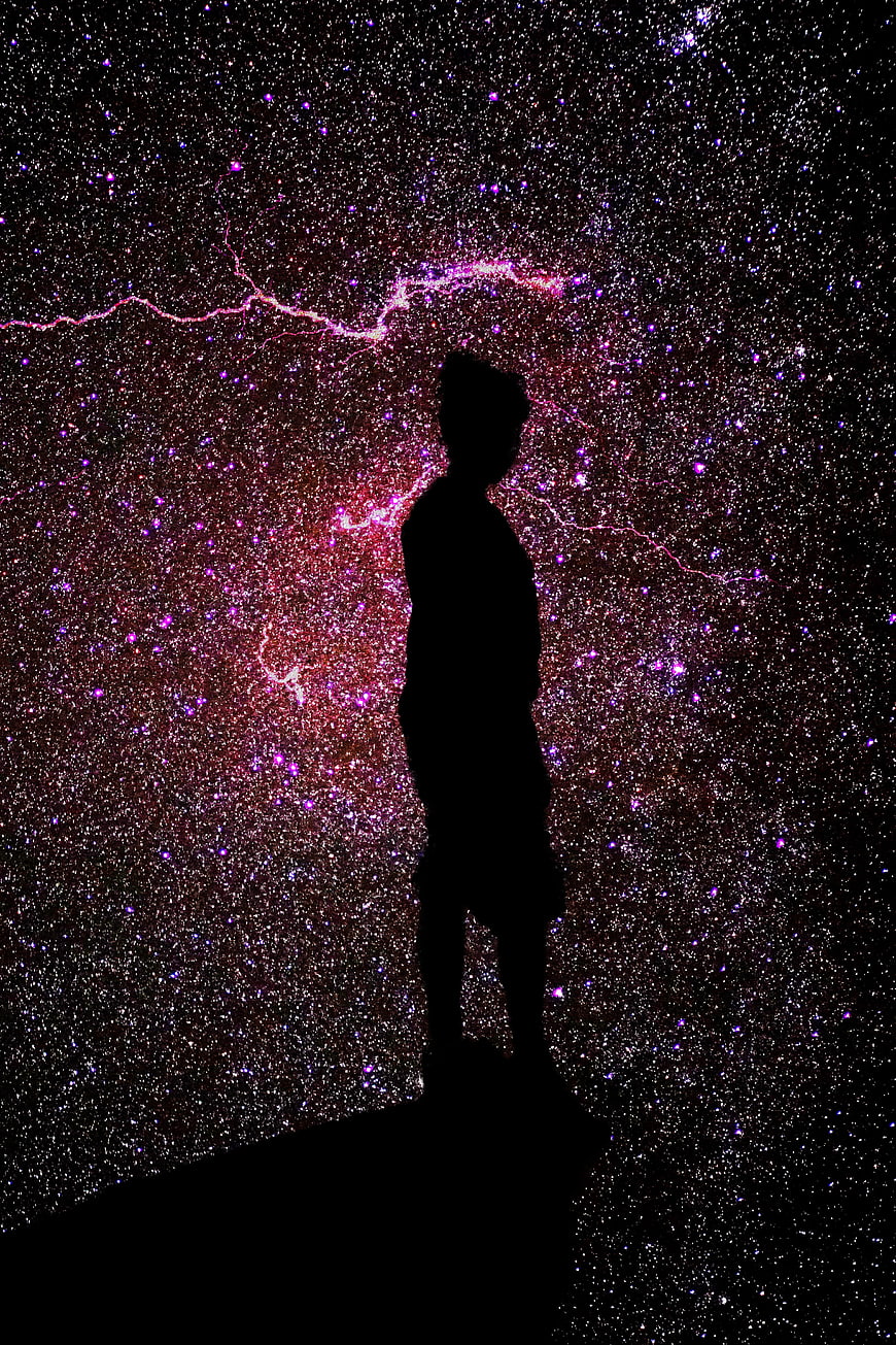 Silhouette of person standing against vibrant starry night sky