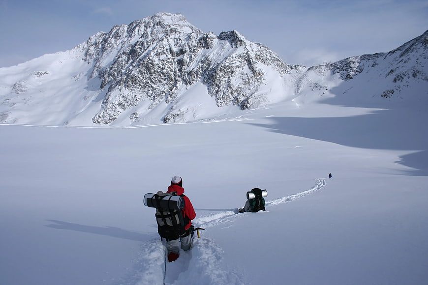 Hikers trekking through snowy alpine landscape