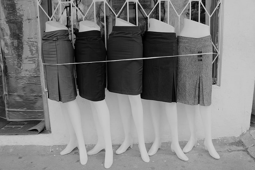 Black and white mannequins wearing skirts in a shop window