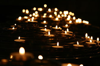 Rows of lit tea candles in a dark church setting