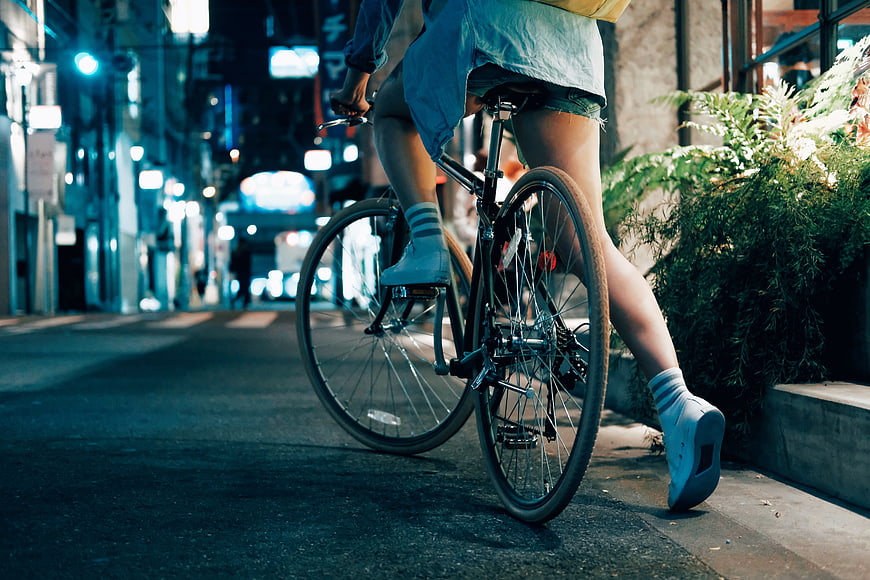 Woman Riding Bicycle on City Street at Night