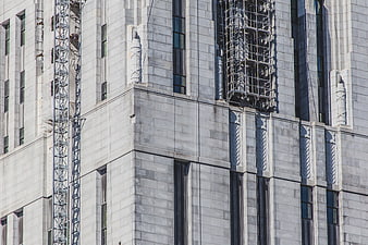Modern gray stone building facade with scaffolding and geometric patterns