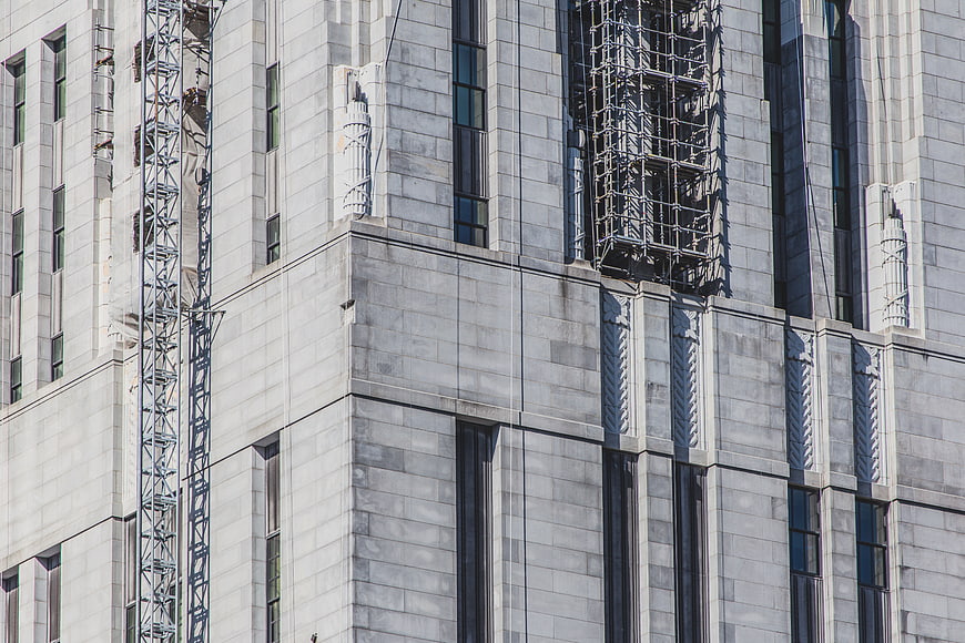 Modern gray stone building facade with scaffolding and geometric patterns