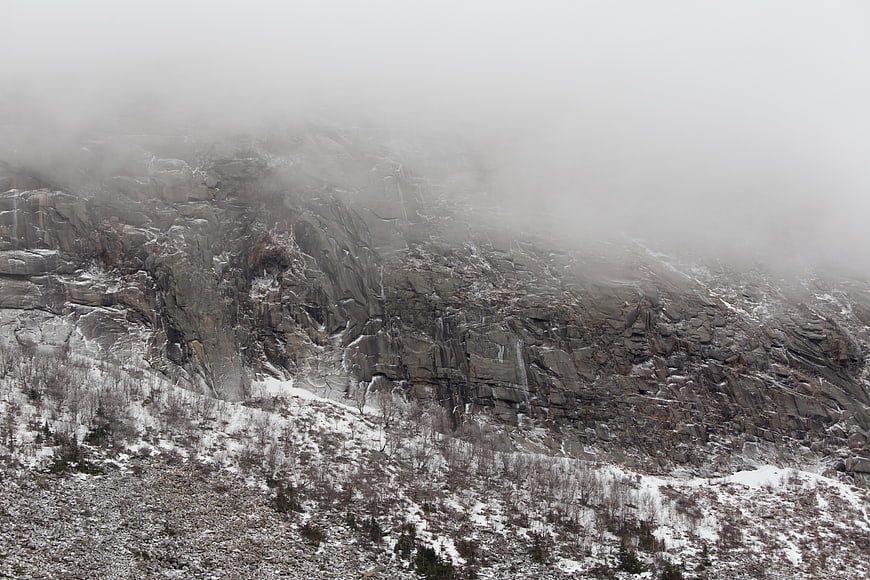 Misty Snow-Covered Rock Cliffs in Winter Landscape