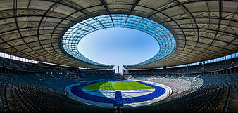 Panoramic view of empty modern stadium with blue track and green field