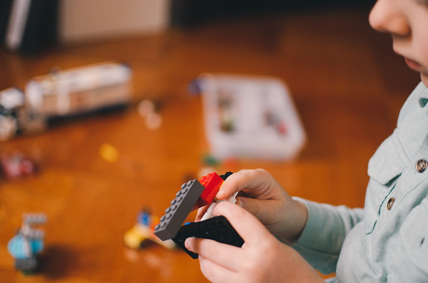 Child Playing with Building Blocks on Wooden Table