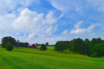 Red Barn And Silo In Green Pasture Under Blue Sky
