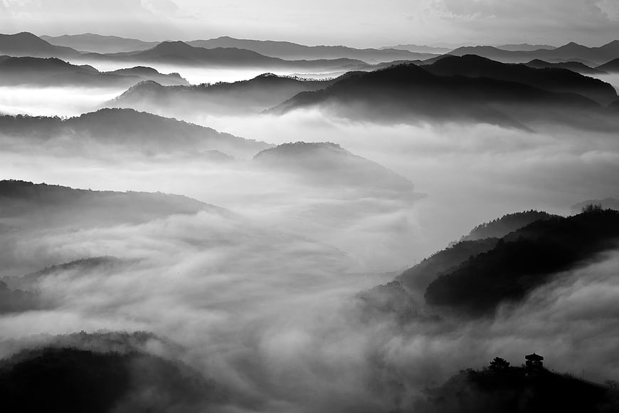 Black and white misty mountain landscape with fog layers