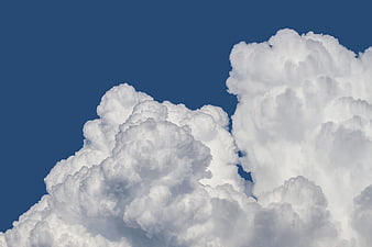 Dramatic white cumulus clouds against deep blue sky