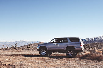 Silver SUV driving on desert road with mountains