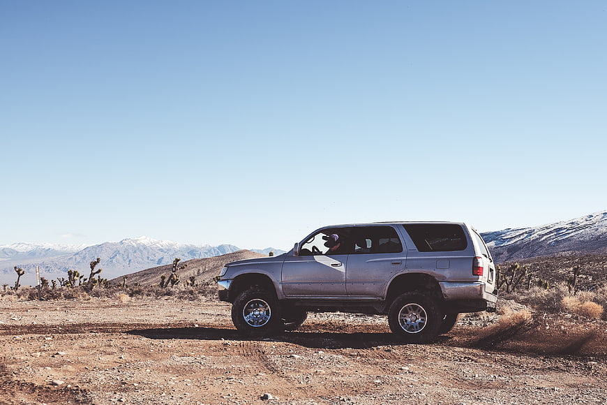 Silver SUV driving on desert road with mountains