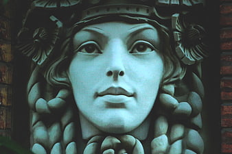 Close-up of vintage stone sculpture face with blue tint