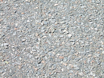 Close-up texture of grey asphalt road surface with stones