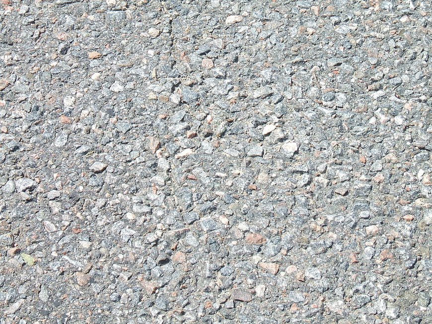 Close-up texture of grey asphalt road surface with stones