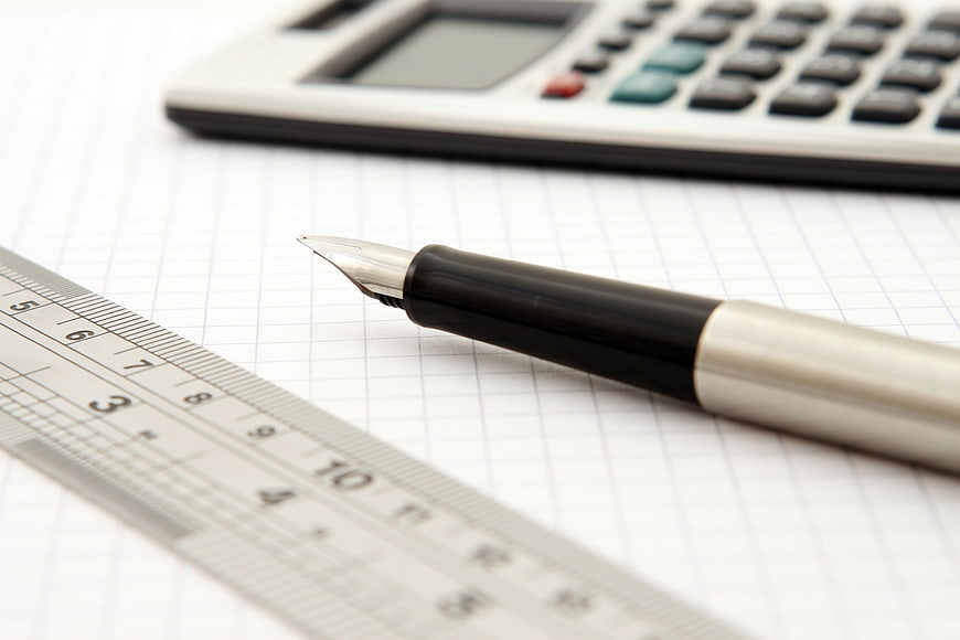 Fountain pen, ruler, and calculator on graph paper