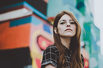 Young Woman with Glasses in Front of Colorful Graffiti Wall