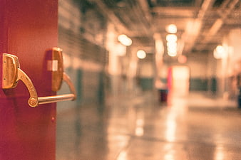 Close-up of brass door handle on red door with blurred hallway background